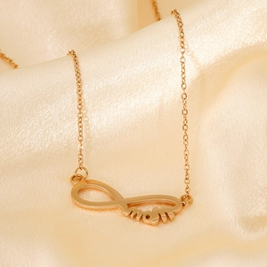 Détail du pendentif infini doré avec inscription mom sur un tissu en soie beige élégant