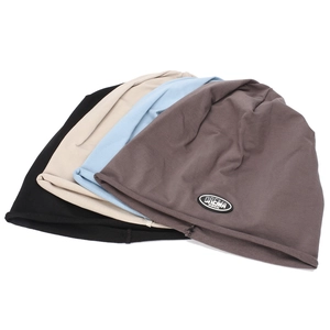 Detailed view of knitted slouchy beanies with leather logo patch and rolled edges
