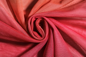 Detailed macro view of vibrant red-orange gradient mesh fabric with breathable texture