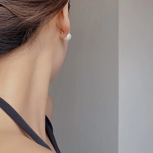 Close-up of model wearing elegant 925 silver pearl stud earrings with a gold finish