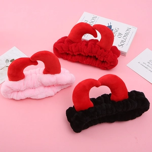 Trois bandeaux en peluche avec cornes de diable en rouge, rose et noir sur fond rose