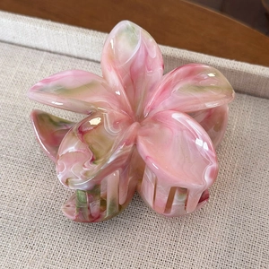 Detailed close-up of marble pink and green frangipani flower acetate hair claw clip