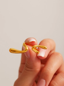 Close-up of a gold-plated irregular wavy ring with high-polish finish on a finger