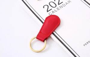 Detail of red PU leather keychain with gold metal ring and creative magnetic fastener