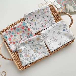 Floral cotton coin purses in four colors on a woven tray with a minimalist rustic aesthetic