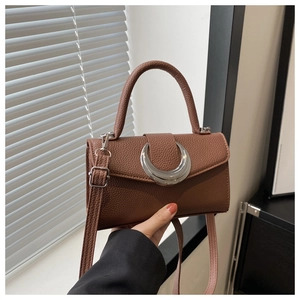Détail d'un sac à main marron en cuir grainé avec boucle métallique argentée en croissant