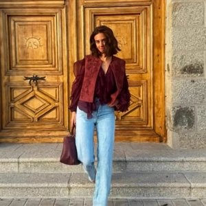 Outdoor shot of a women's vintage red embroidered vest with long-sleeve ruffle shirt