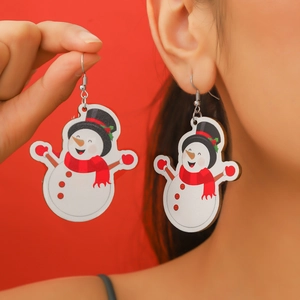 Close-up of cute Christmas snowman earrings with red scarf and black hat on festive red backdrop