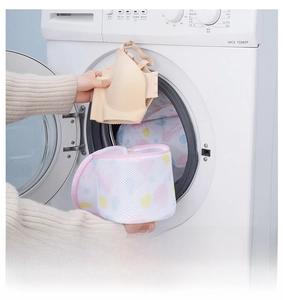 Close-up of heart print mesh laundry bag with pink zipper being placed in a washing machine