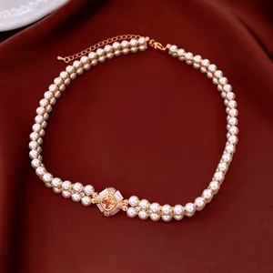 Vintage double-layer pearl necklace with a gold-plated gemstone pendant on red silk