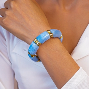 Detailed close-up of blue marble acrylic tube beads and gold metal spacers on the wrist
