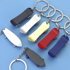 Miniature metal skateboard and surfboard keychains in various metallic colors on blue background