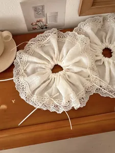 Detail of cream lace scrunchie with bow and rhinestone on a vintage wooden desk