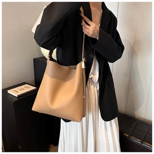 Detail of brown pebbled leather tote bag with gold metal buckle on a shoulder strap