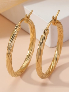 Macro view of gold twisted stainless steel hoop earrings with elegant spiral texture