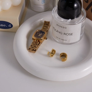 Detail shot of gold-plated rectangular watch and zircon earrings in a luxury setting