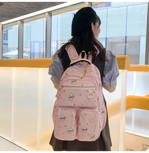 Back view of pink bear backpack with multiple pockets worn by a model in a mall