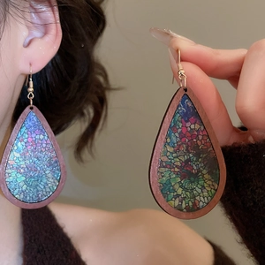 Detail of ethnic teardrop earrings featuring wood frames and colorful mosaic patterns