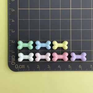 Flat lay of small colorful resin bone charms for DIY crafts and nail art on a scale mat