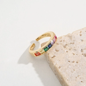 Adjustable gold ring featuring geometric rainbow cubic zirconia stones on stone surface
