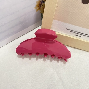 Close-up of a large rose red acetate hair claw clip on a white fabric background