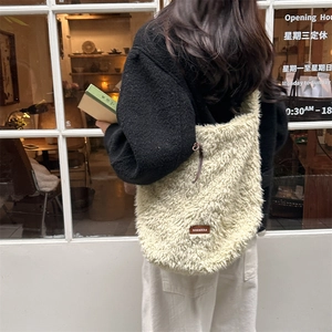 Detail of creamy plush tote bag with leather logo patch and drawstring on furry texture