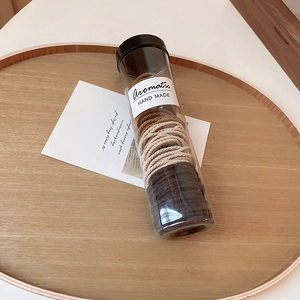 Detail view of elastic hair ties in brown, beige, and black within a clear storage tube