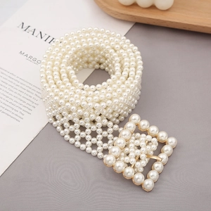 Detail of woven pearl belt featuring a golden square buckle on grey fabric texture