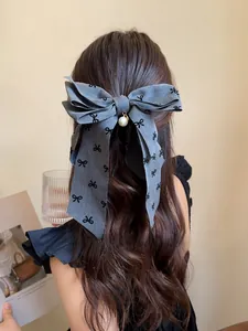 Dettaglio della pinza per capelli grigia con fiocco e perla su lunghi capelli ricci