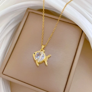 Detailed macro shot of gold fish pendant necklace with sparkling white cubic zirconia