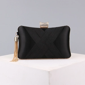 Detailed view of a black evening clutch with pleated satin texture and tassel hardware