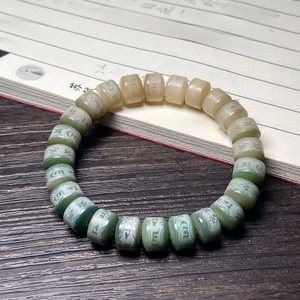 Close-up of Bodhi root beads with Six-Character Mantra carvings on dark wood background