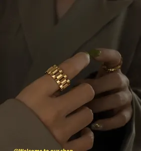 Detail view of a gold-plated stainless steel watchband link ring on a model hand