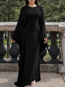 Détail d'une élégante robe longue noire en tissu plissé avec de larges manches longues
