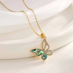 Macro view of gold butterfly pendant with iridescent shell inlay and sparkling crystals