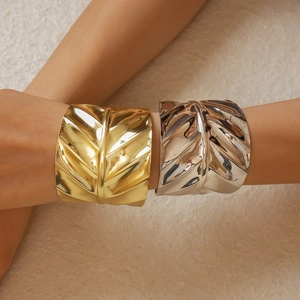 Detail showing leaf vein textures on gold and silver wide cuff bracelets on model