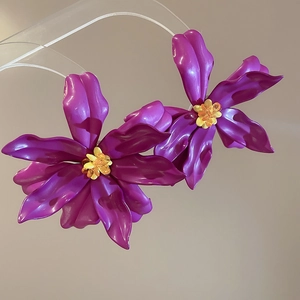 Detailed close-up of purple acrylic flower earrings with vibrant yellow beaded centers