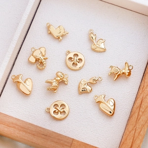 Detail of assorted gold elephant and heart charms for DIY jewelry making on wood tray