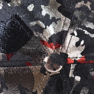 Macro shot of gold and silver metallic foil patterns on a black textured baseball cap