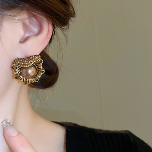 Gros plan de boucles d'oreilles dorées vintage avec perle brune et strass brillants