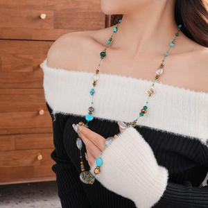 Detail of bohemian layered necklace featuring turquoise beads and vintage metal butterfly charm