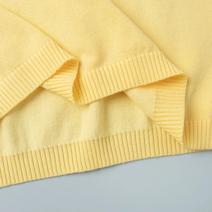 Close-up of bright yellow knitted top showing detailed ribbed texture on hem and sleeves