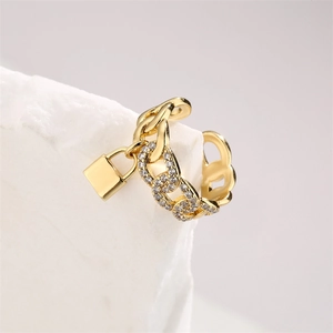 Detailed view of a gold chain ear cuff with a micro-paved diamond lock pendant on a model