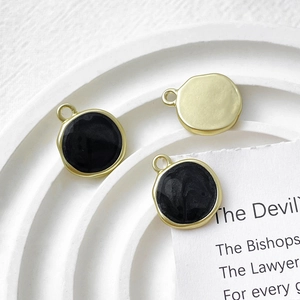 Detail view of round gold enamel charms on a textured tray for DIY jewelry making