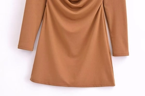 Detailed close-up of the elegant draped hem and soft textured fabric of a camel midi dress
