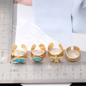 Gold Evil Eye ring set with starfish and crystal details on a fashion magazine background