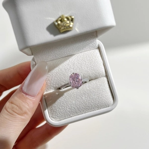 Close-up of an oval pink ice cut cubic zirconia ring set in silver with pavé diamond band
