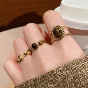 Detail of 18k gold plated tiger eye stone rings on hand with vintage aesthetic