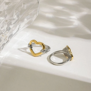 Vue détaillée de la bague coeur bicolore sur fond blanc avec ombres artistiques d'eau