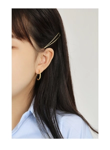 Close-up of minimalist golden hoop earrings and hair clip worn by a model for a chic look